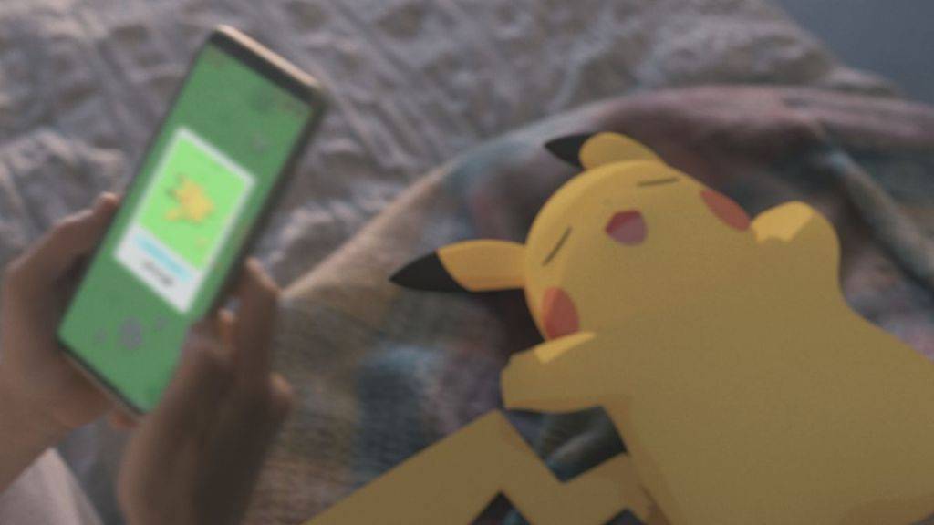 昏昏欲睡的皮卡丘的圖像，一個人使用Pokemon睡眠應用程序拿著電話
